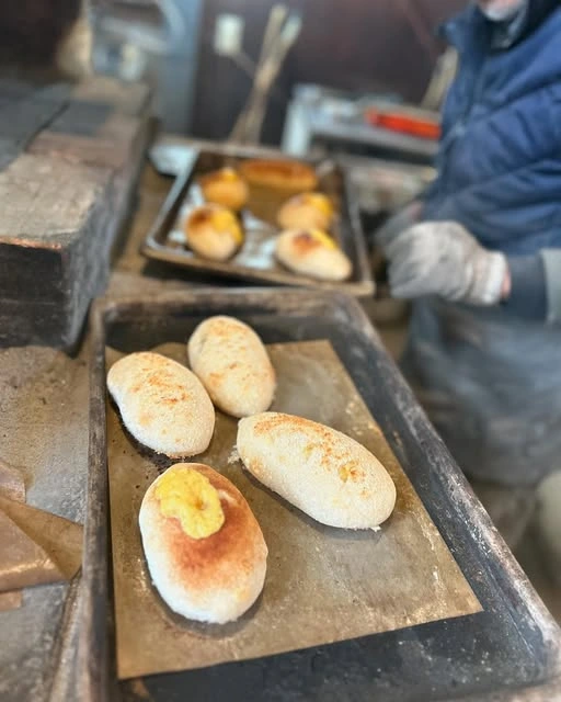 薪窯の前で、天板に並ぶ焼きたてのパン